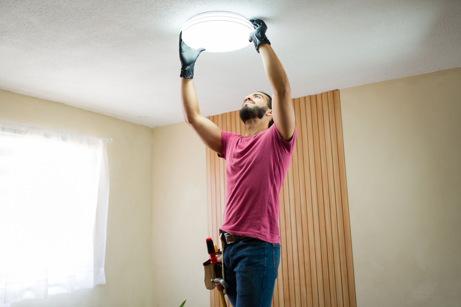Handyman installing ceiling light fixture in residential home